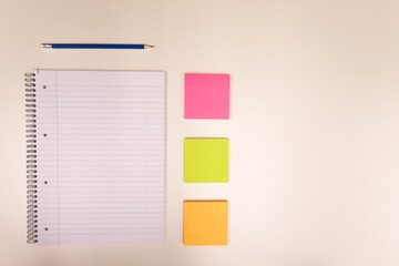 Notepad, pencil and small coloured note on a white desk