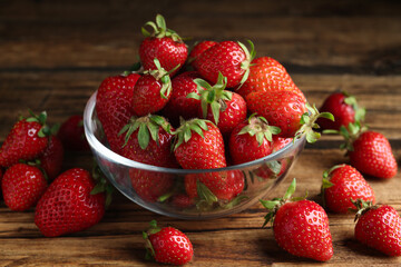 Delicious ripe strawberries in glass bowl on wooden table