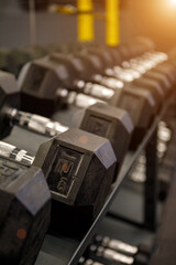 Black dumbbell set in the gym. Close up many metal dumbbells on rack in sport fitness center. Weight Training Equipment concept.