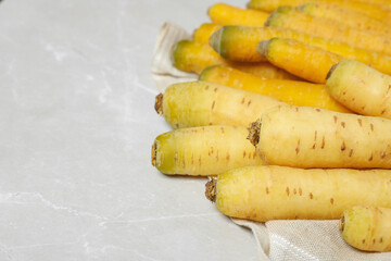 Raw white and yellow carrots on light grey marble table, closeup