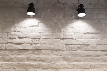 a white brick wall and two glowing lamps
