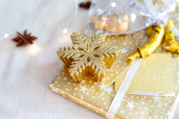 Geschenk für Weihnachten mit goldenem Papier und weißen Sternen und einer goldenen Kerze