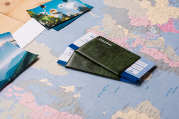 Passports and tickets placed on paper world map with scenic photos, travel concept