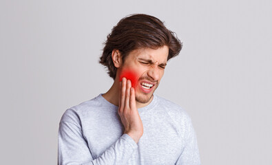 Endure pain. Sad man suffers from pain in his teeth and presses hand to red spot