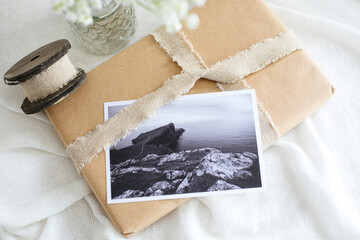 Gift wrapped in beige wrapping paper. On it is a postcard with a picture of Neist Point in Scotland.