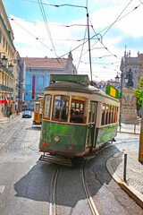 Fototapeta premium Historic green tram against old town streets, part of the tramway network since 1873, Lisbon, capital city of Portugal.