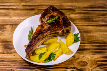 Plate with roasted ribeye steak and potatoes on wooden table