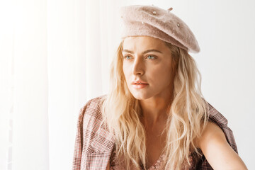 Beautiful blonde fashion woman in brow checked dress. Trendy young woman in shabby chic white interior.