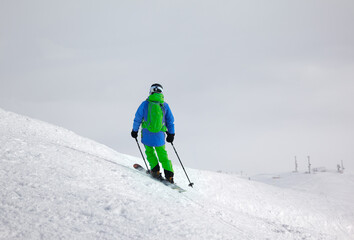 Skier before downhill on freeride slope and overcast misty sky