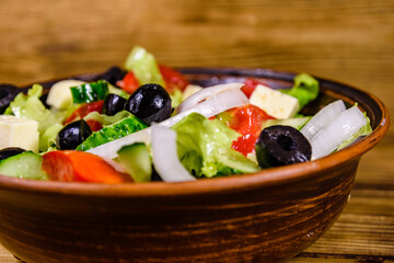 Ceramic plate with greek salad on wooden table