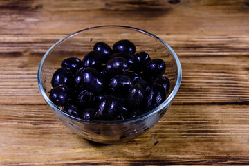 Glass bowl with black olives on wooden table