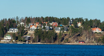 Picturesque summer houses painted in traditional falun red on dwellings island of the Stockholm archipelago in the Baltic Sea in the early morning.