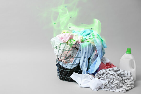 Laundry basket with dirty clothes on grey background