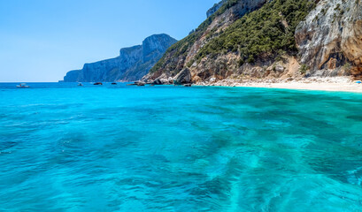 Naklejka na ściany i meble Sardinia, holidays, White sand beach, sea with crystal clear azure water, mountains in the background. Italy, the best beaches in Sardinia.