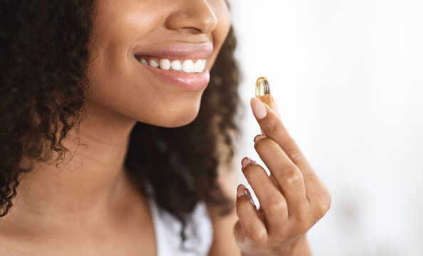 Beauty Supplement. Smiling Black Girl Taking Biotin Vitamin Capsule For Healthy Skin
