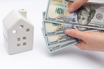 White house with cash dollar banknotes in hands, as a symbol of bank credit taken as a loan.