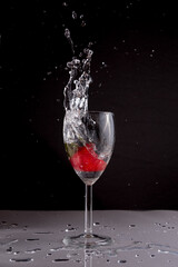 A strawberry dropping into a glass of water creating a splash. 