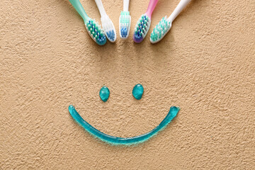 Toothbrushes and smile made of paste on color background
