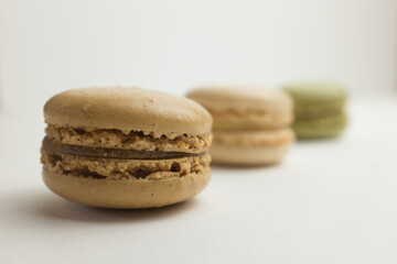 A row of three pastel coloured macarons indoors against a soft neutral background.