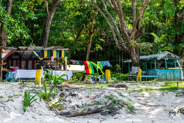 Vendor shops on seashore in Portland, Jamaica, made of bamboo & zinc. Colorful beach towels, clothes and jewelry of Jamaican flag and Rasta/ Rastafarian colors.