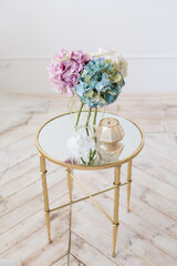 Tender simple  interior in light colors with tule, bouquets of artificial hydrangea and elegant  mirror table on light parquet floor