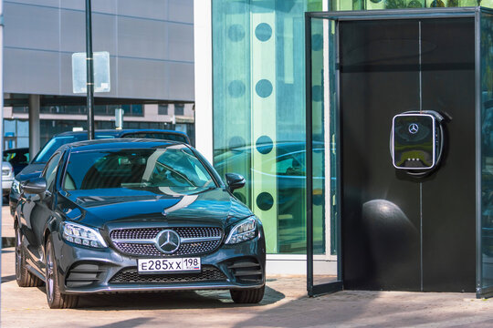 Black Mercedes-Benz three car store Mercedes, power supply plugged into. Electric car charging on parking lot with electric car charging station on city street.. Russia, Saint-Petersburg. 14 may 2020.