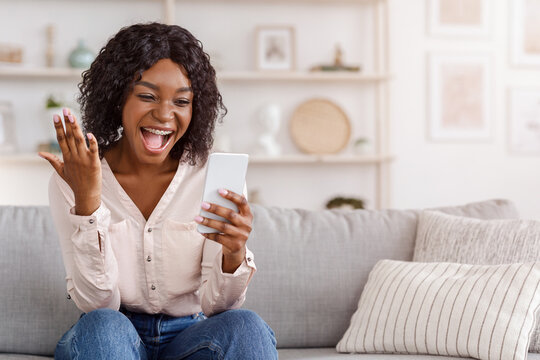 Overjoyed black girl celebrating success with smartphone at home, received good news