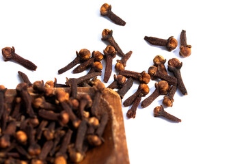 dried cloves in a wooden dish and clear cloves on a white background.