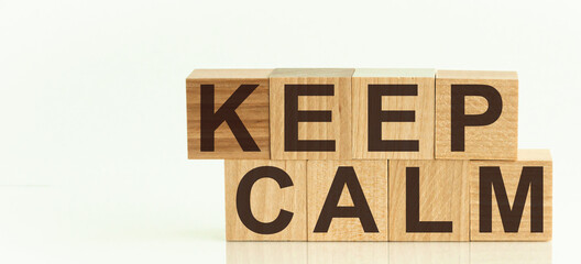 KEEP CALM - text on wooden cubes on a white gradient background.