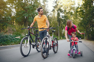 Fototapeta premium Family in a park. People with a bicycle. Parents with little daughter.
