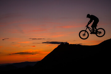 Fototapeta premium BARDENAS, SPAIN. A mountain biker jumping against sunset sky in the Spanish desert