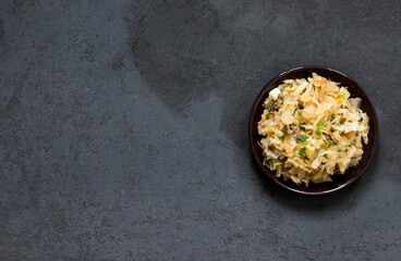 Cabbage stewed with carrots and green onions on a plate on a dark gray background top view copy space