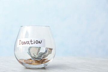 Glass bowl with money on light background. Donation concept