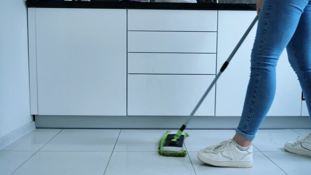 Woman washing white kitchen floor with special swob, cleaning service, close-up