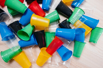 A large pile of multicolored plastic cups scattered on the floor. Pollution of the environment by human waste