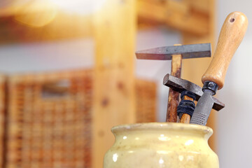wooden hammer and rape craftsman tools in a pot placed on a wooden workbench in a carpentry...