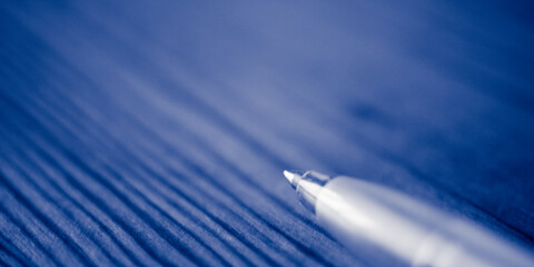 Ball pen on the blue wooden table. Macro photo, side view.