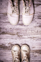 Big and small shoes on wooden background. Still life photography : father and child shoes on old wood in vintage color tone, go ahead together and fathers day concept.