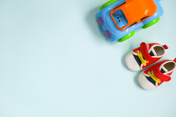 Baby boy goods. Plastic toy car and tiny sneakers on blue background. Copy space.