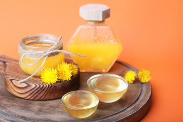 Jars of dandelion honey on color background