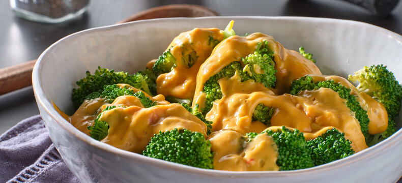 steamed broccoli with melted cheddar cheese sauce in bowl