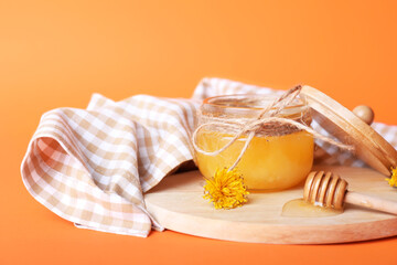 Jar of dandelion honey on color background