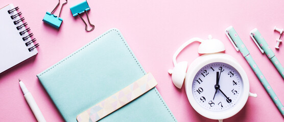 Pen, alarm clocks and other stationery close-up on a pink background
