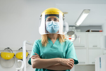 Mujer dentista con mascarilla y equipo de protección individual, EPI, garantizando la máxima seguridad para los pacientes en contra del coronavirus COVID-19 - obrazy, fototapety, plakaty