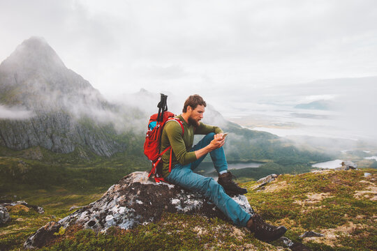 Man using smartphone hike in mountains travel blogger influencer lifestyle adventure vacations summer tour outdoor in Norway