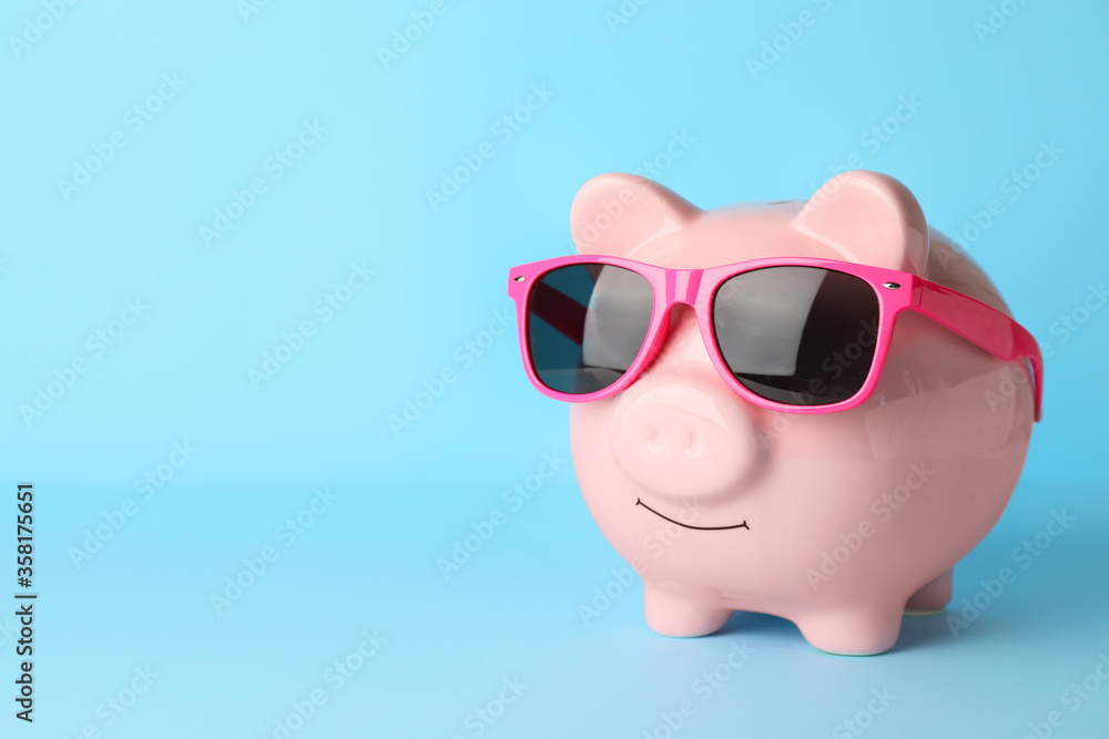 Wall mural piggy bank with sunglasses on color background