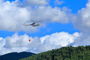 Fototapeta na wymiar Firefighting helicopter intervenes for the fire that starts on the forest-covered mountain.