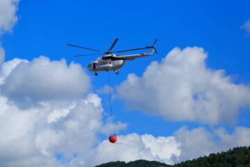 Fototapeta na wymiar Firefighting helicopter intervenes for the fire that starts on the forest-covered mountain.