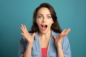 young woman screaming and gesturing with hands on blue background
