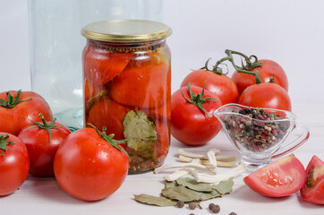 Canning tomatoes. Red ripe tomatoes in a jar with spices on a white background. Autumn harvesting